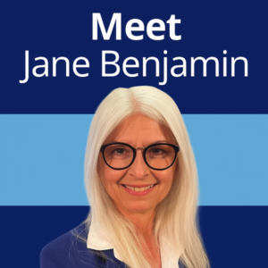Square 600×600 graphic in dark and light blue with large white Open Sans-style headline “Meet Jane Benjamin” at the top, and a smiling professional headshot of a woman with long white hair and black glasses on the lower right; no other logos or text